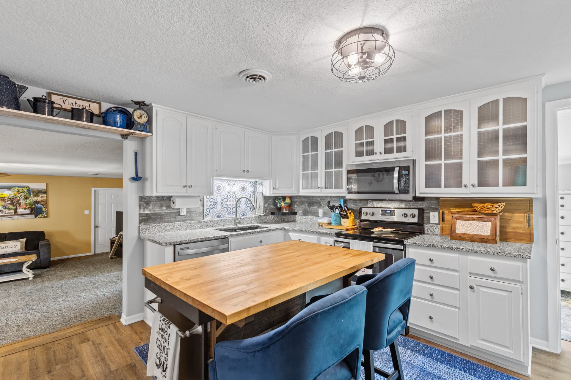 Kitchen with white cabinetry, granite counters and butcher block island
