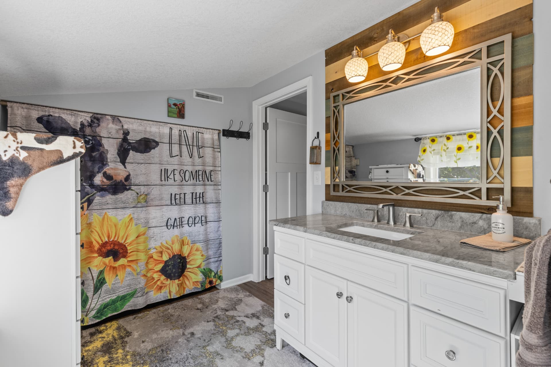 Full bathroom with white vanity, stone counter and reclaimed wood accent wall