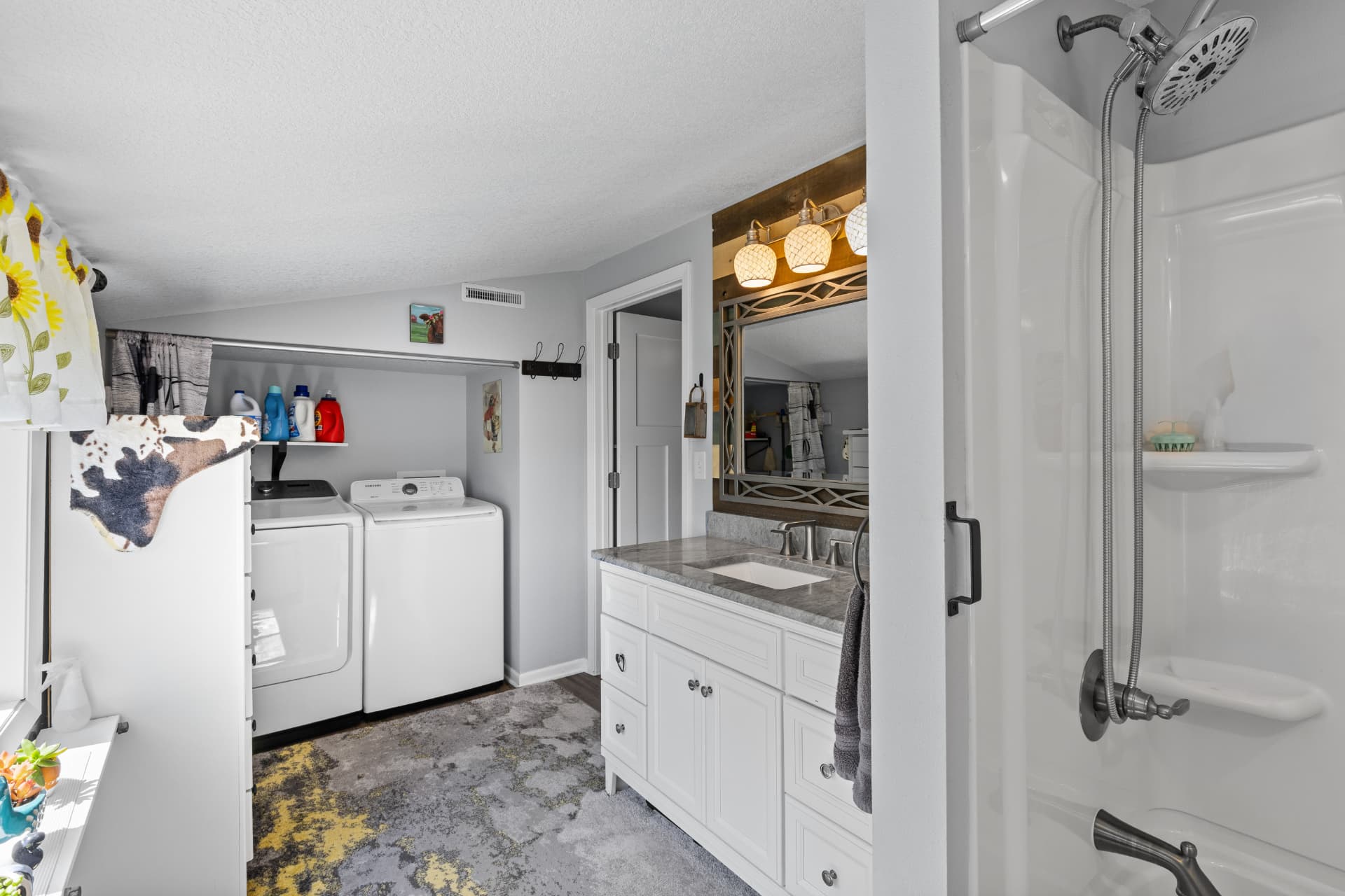 Main level laundry area with washer and dryer next to the bathroom vanity and shower