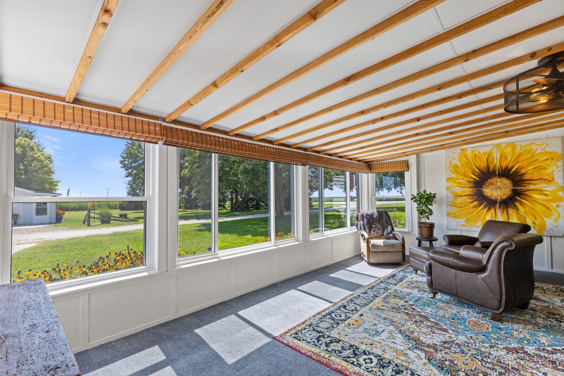 Southwest facing 3-season sun porch with wall of windows overlooking the yard and farm field